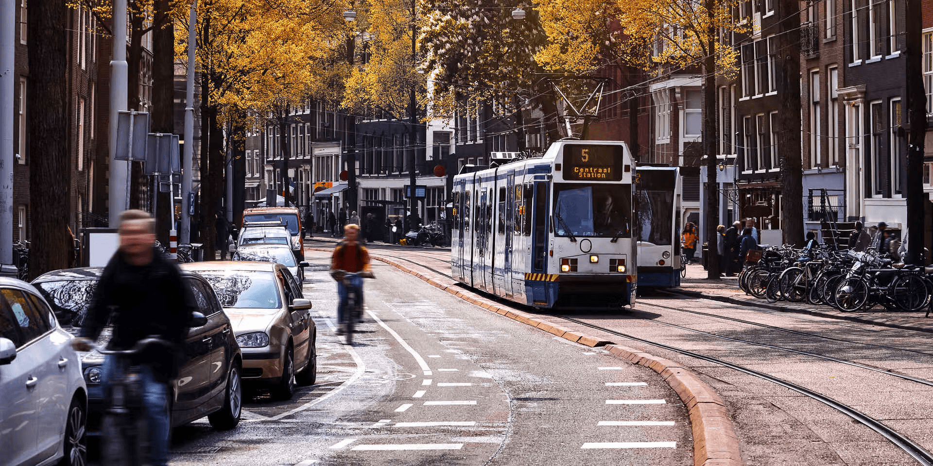 Amsterdam street scene with tram, cyclists, and autumn trees