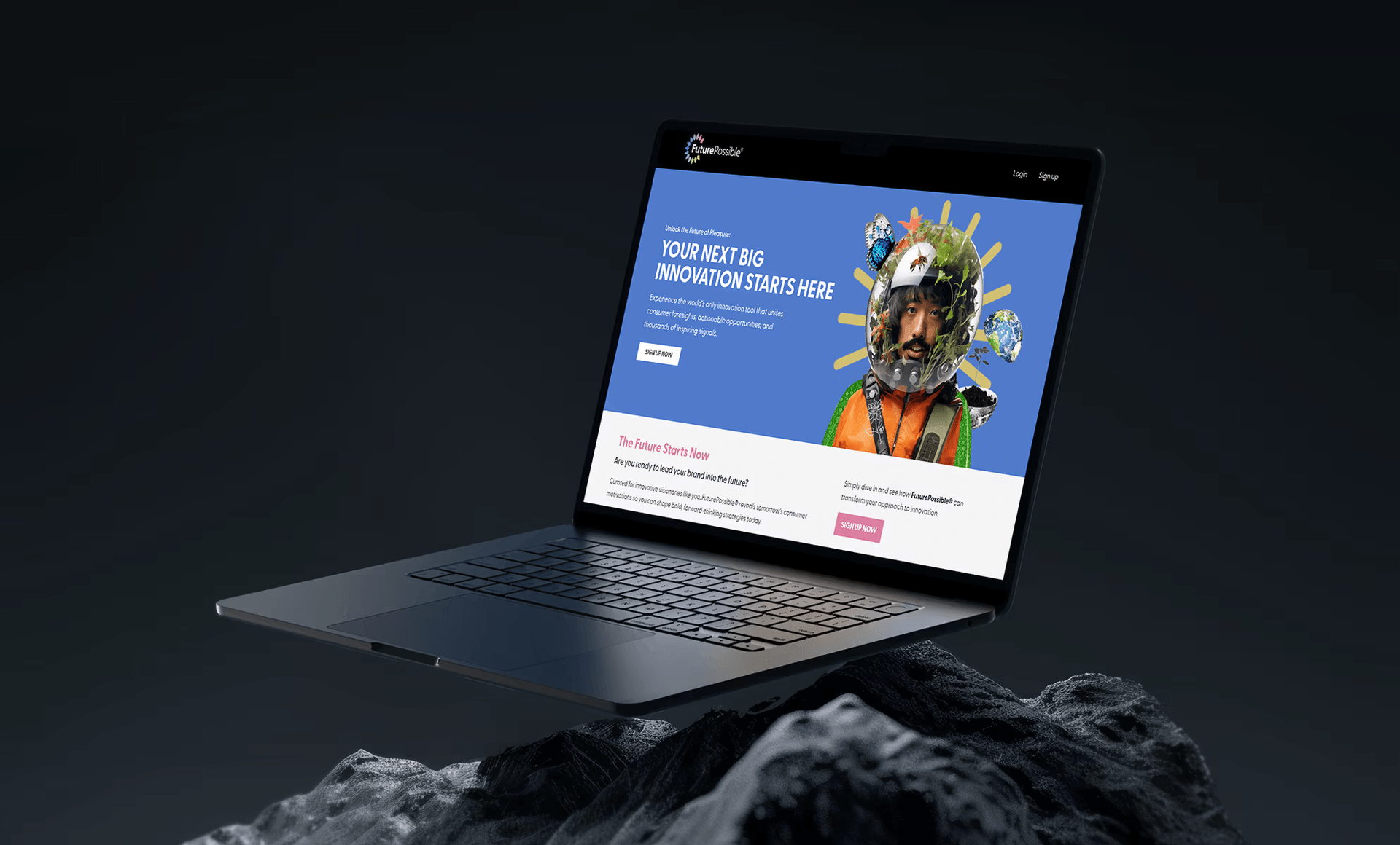 Laptop displaying website with colorful artistic portrait on dark rocky surface