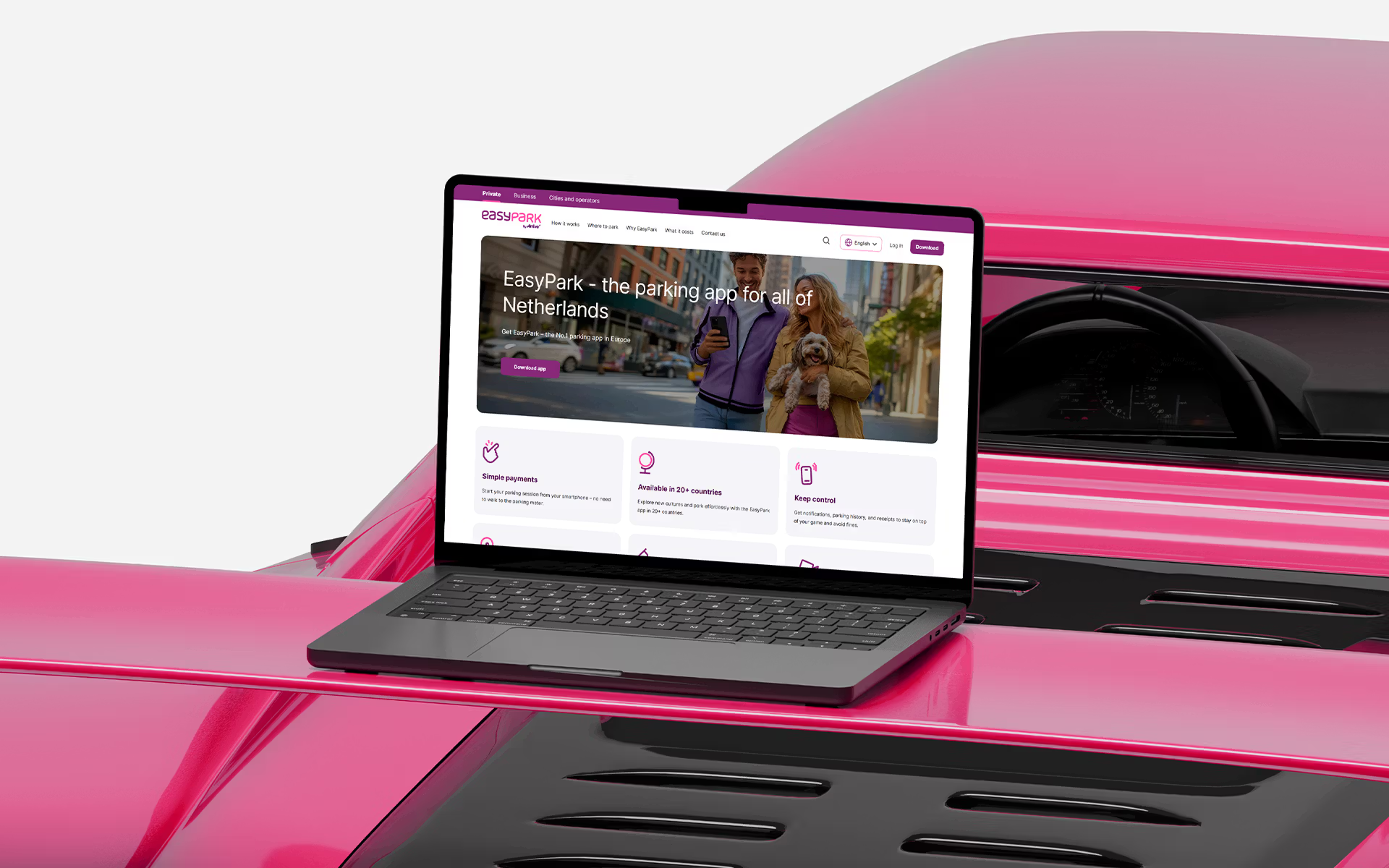 Laptop on pink surface showing a website with colorful hero section
